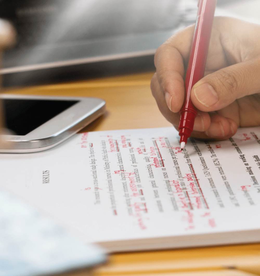 Person making corrections using a red pen to a typed document.